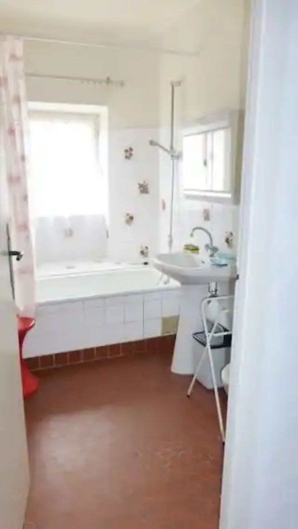 A small, white bathroom with a bathtub, a sink, and a mirror.