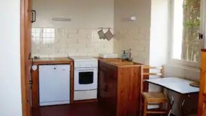 Une cuisine de taille réduite, équipée d’un réfrigérateur, d’une cuisinière et d’un comptoir en bois.