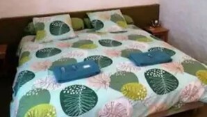 Une chambre à coucher avec un lit, une table de chevet et un tableau encadré accroché au mur.
