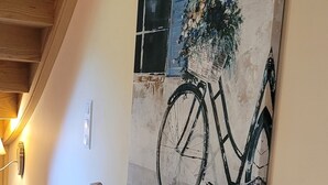 Un pasillo con un banco de madera, un cuadro colgado en la pared de una bicicleta y una lámpara.