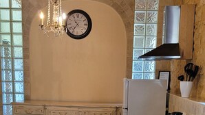 Una cocina con vigas de madera, un candelabro, un reloj, un refrigerador y un ventanal con vistas.