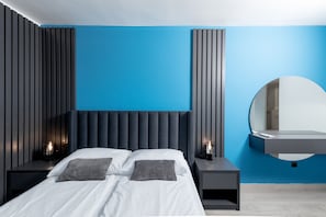 A modern bedroom with a bed, bedside tables, a mirror, and a blue accent wall. - Boutique Suites Joyce Medulin (Medulin)
