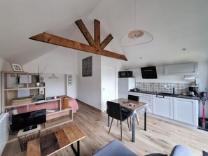 A modern kitchen with white cabinets, a wooden dining table, and a hanging light fixture. - Studio, a 5-minute walk from the beach (TREGUNC)