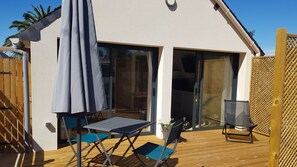 A patio with a table and chairs, a sliding glass door, and a wooden deck. - Studio, a 5-minute walk from the beach (TREGUNC)