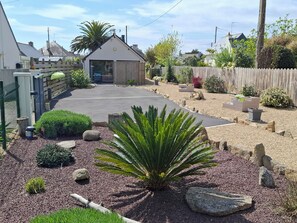 A residential garden with a paved driveway, various plants, and a wooden fence. - Studio, a 5-minute walk from the beach (TREGUNC)