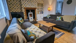 A cozy living room with a sofa set, a coffee table, and a fireplace. - Gorgeous Comrie Cottage, hot tub & Mountain Views (Crieff)
