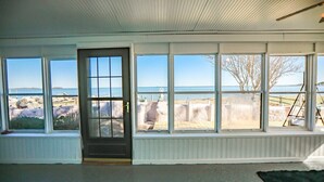 Quarto com grandes janelas que oferecem vista para o mar e um litoral rochoso.