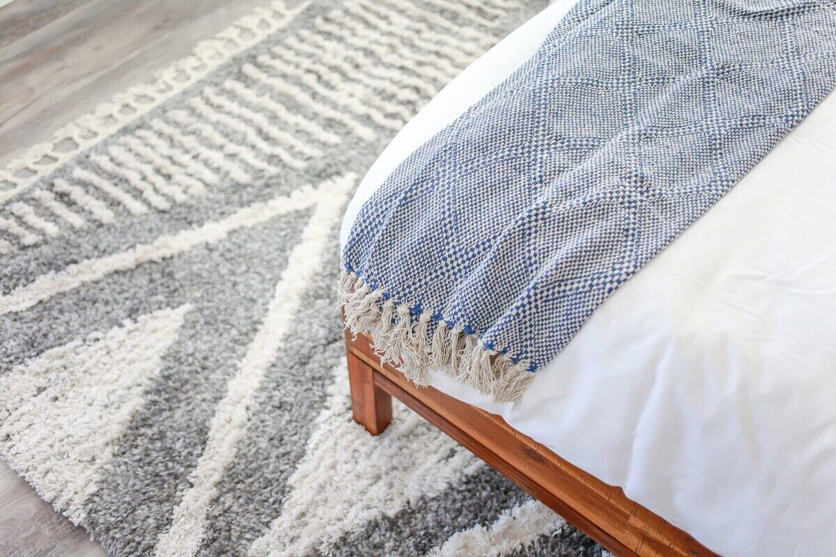 Ein Bett mit einem weißen Kopfkissen und einer Decke mit blau-weißen Mustern.