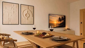 A dining area with a wooden table, chairs, and a view of the sunset.