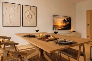 Un espace repas avec une table en bois, des chaises et une vue sur le coucher de soleil.