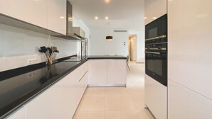 A modern kitchen with white cabinetry, a black countertop, and built-in appliances.