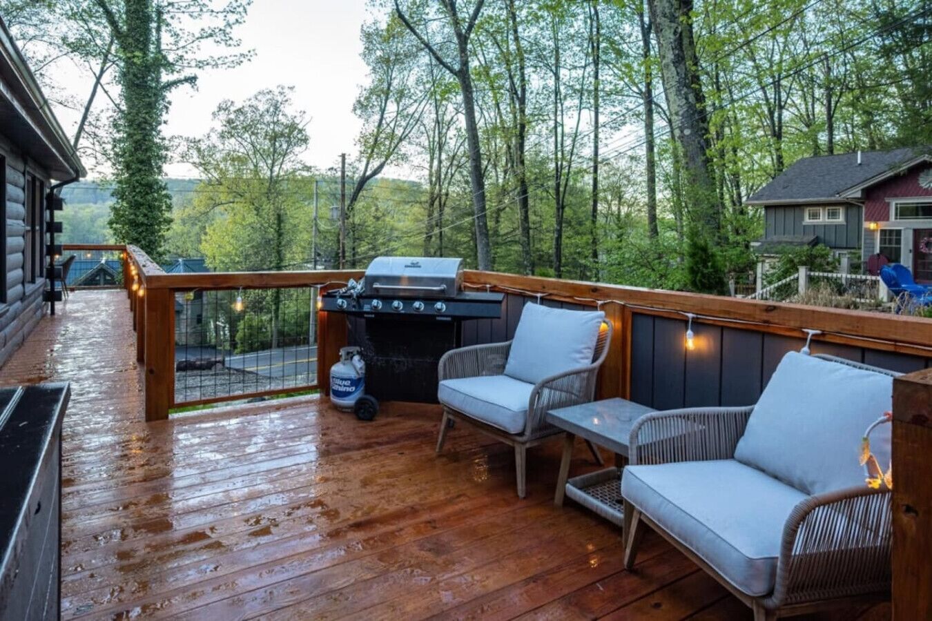 Eine Holzterrasse mit Grill und zwei Korbstühlen.