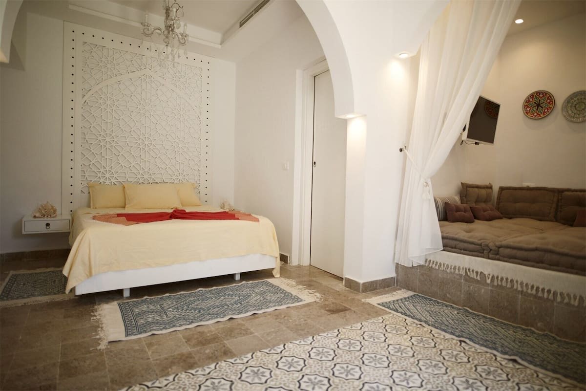 Ein Schlafzimmer mit einem Bett, einer Couch, einer Wandverkleidung und einem Teppich mit Muster.