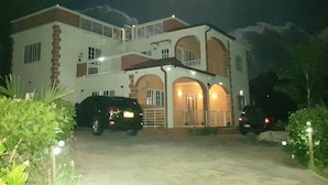 A two-story house with a driveway and parked cars. - Beautiful 1-bed Apartment in Saint George's (St. George's)