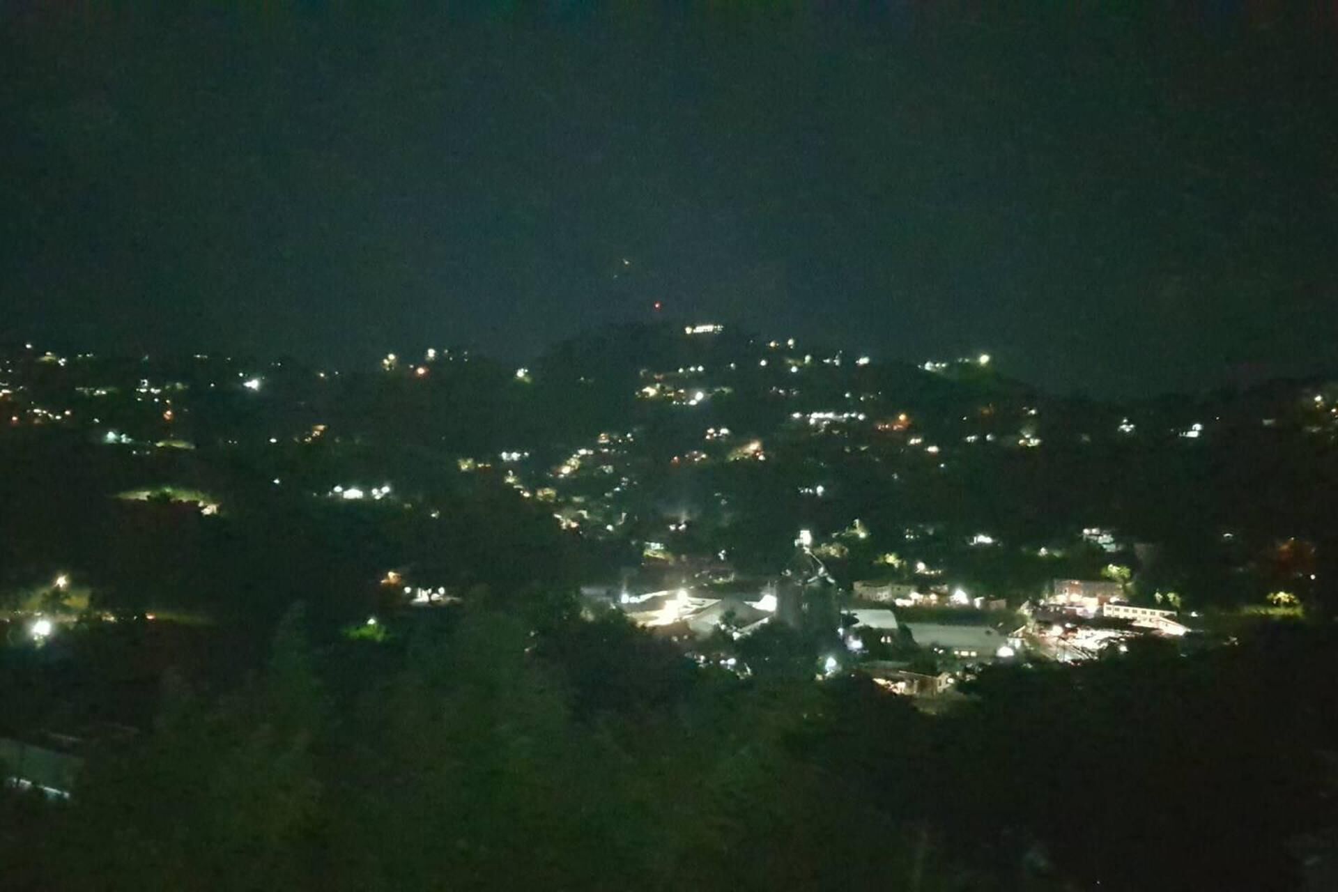 Ein nächtlicher Blick auf eine Stadt mit vereinzelten Lichtern, die Gebäude und Straßen zeigen.
