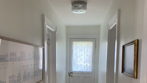 Ein Flur mit Holzboden, weißen Wänden, einer Tür mit Fenster und einer gerahmten Karte an der Wand.