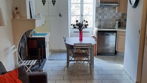 A compact living space with a sofa, a coffee table, and a dining area with a table and chairs. A kitchen is visible in the background with cabinets and a stove.