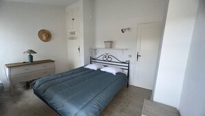 A bedroom with a bed, a nightstand, a dresser, a hat on the wall, and a door.