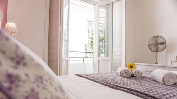 A bedroom with a bed, a window, a fan, and a towel with a flower. - Lalitana Townhouse (Lagos)