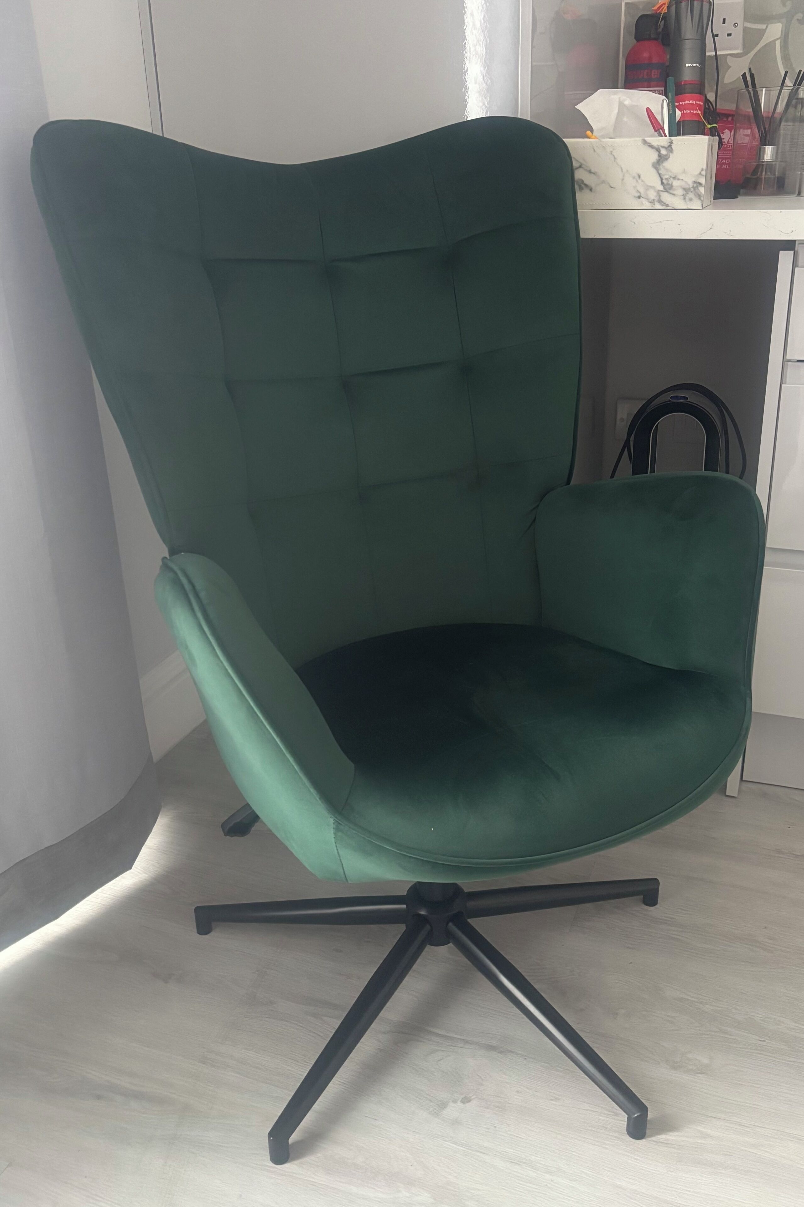 A green office chair with a cushioned backrest and a five-point swivel base.