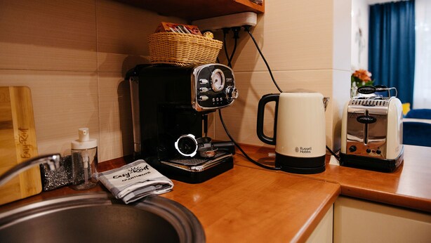 Uma cozinha compacta com cafeteira, torradeira e uma cesta sobre o balcão.