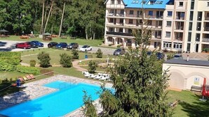 Un hotel con piscina, varios balcones y zona de estacionamiento.
