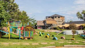 A playground with colorful equipment and a building under construction in the background. - GALORE LUXURY RESORT (Kisumu)