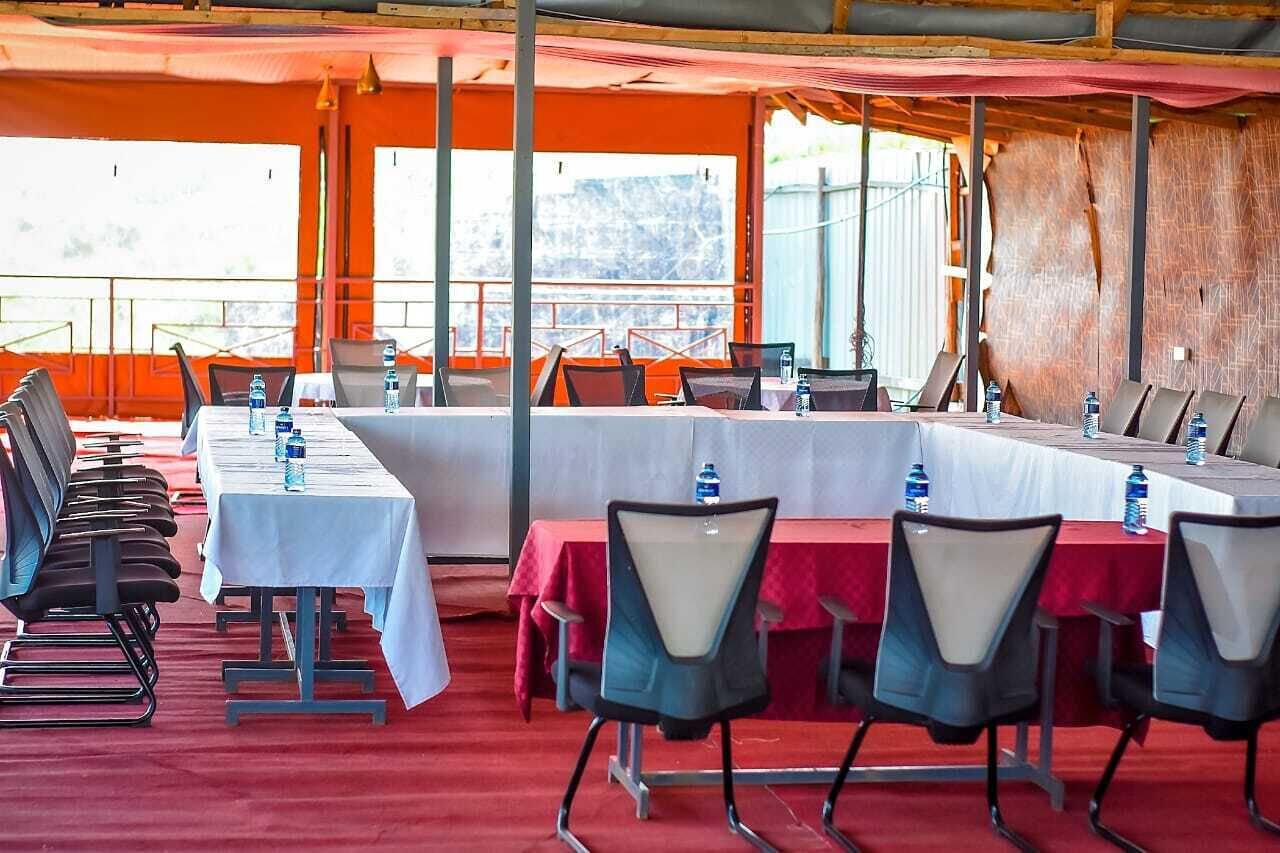 Une salle de conférence avec de longues tables et des chaises, de grandes fenêtres et un tapis rouge.