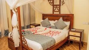 A four-poster bed with a canopy, wooden headboard, and two bedside tables with drawers. - GALORE LUXURY RESORT (Kisumu)