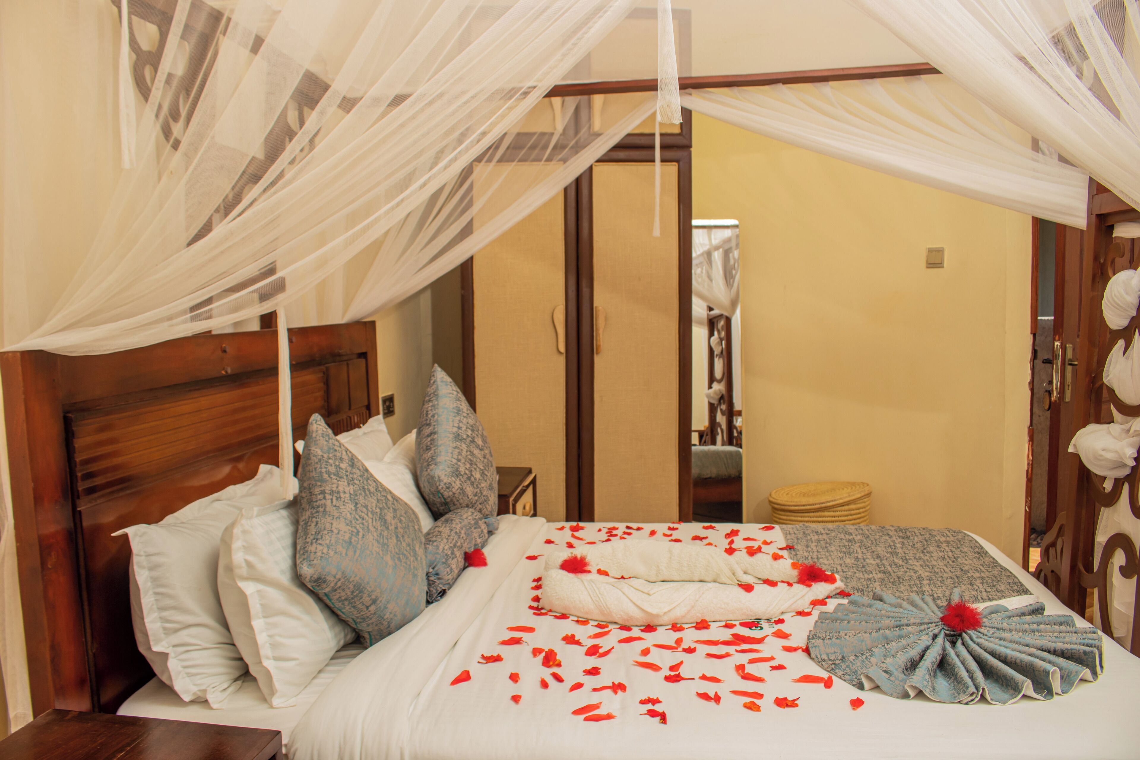 A neatly made bed with white and blue linens, a wooden headboard, and a canopy.