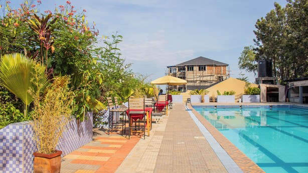 A pool area with lounge chairs and a building in the background. - GALORE LUXURY RESORT (Kisumu)