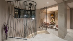 Un interior moderno con una escalera espiral, una zona de comedor con mesa y sillas, y un jarrón decorativo con flores.