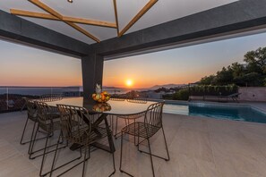A rooftop terrace with a dining table and chairs, a pool, and a sunset view. - Aurelia 8 (Makarska)