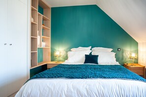 Quarto com cama, duas mesas de cabeceira, um criado-mudo, estante embutida e luminária na parede.
