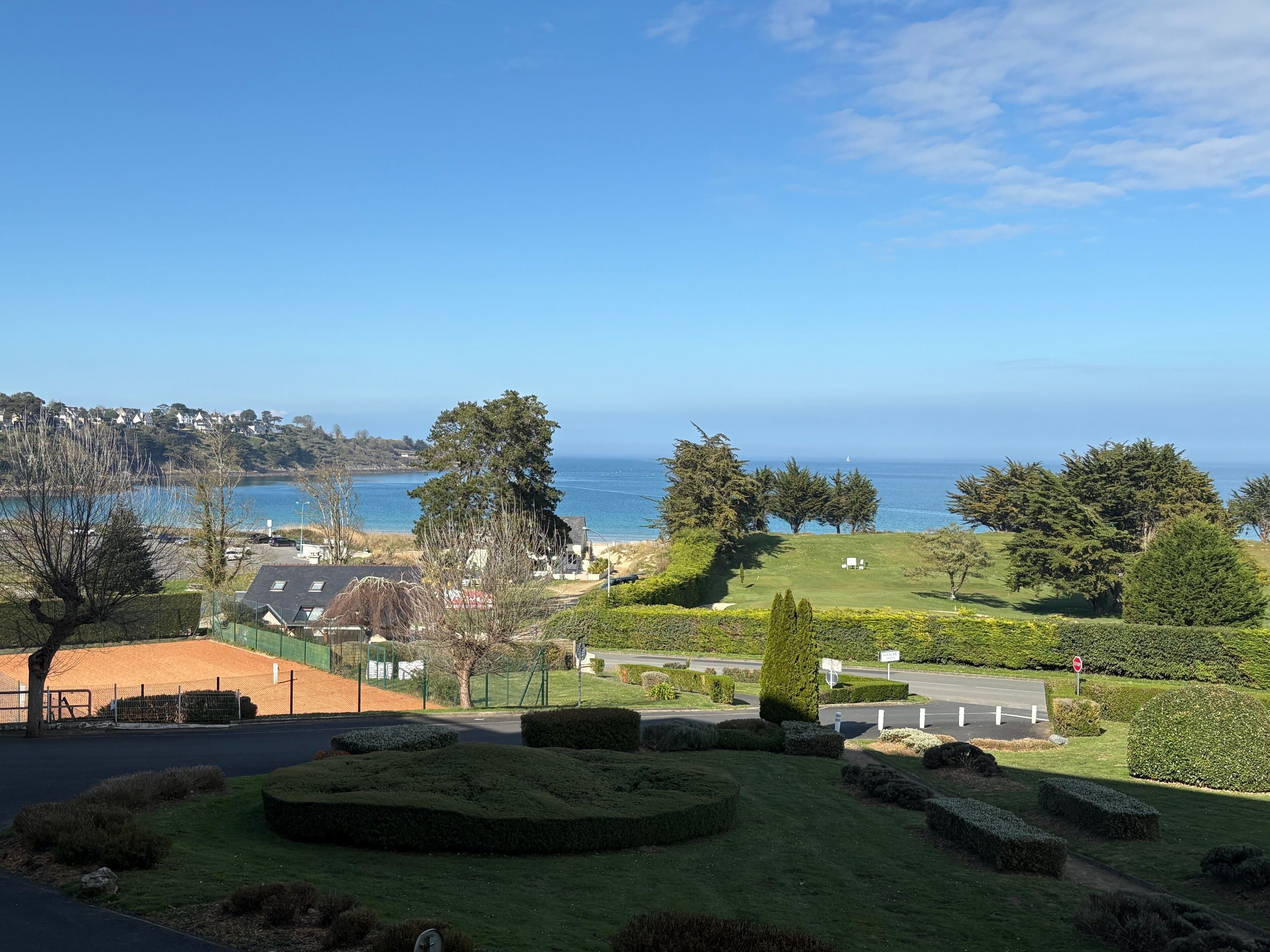 Blick auf die Küste mit einer gepflegten Rasenfläche, einem Golfplatz und blauem Himmel.
