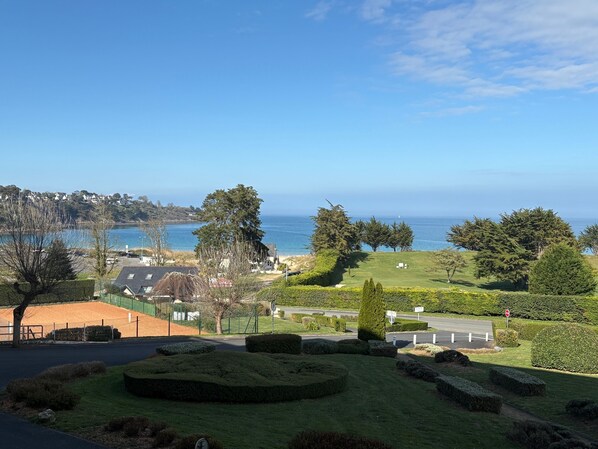 A coastal view with a well-maintained lawn, a golf course, and a clear sky.