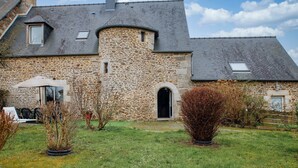 A stone house with a sloped roof, a small garden, and a visible door. - Tour des Alleux - Maison de maître pour 6 (Taden)