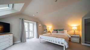 A bedroom with a bed, a TV, a dresser, and a window with curtains. - Ranch House Cottage · Ranch House Cottage, Inverurie, Aberdeenshire (Aberdeenshire)