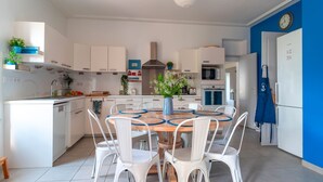Eine moderne Küche mit weißen Schränken, einem Holzespeisetisch mit weißen Stühlen und einer blauen Wand.