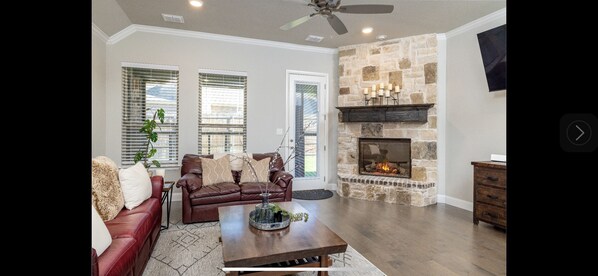 A living room with a stone fireplace, leather sofa, and a coffee table.