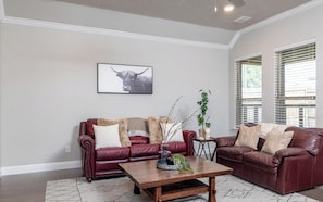A living room with two leather sofas, a wooden coffee table, and a framed bull picture on the wall.