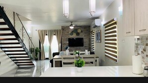 Una cocina moderna con una isla central, un comedor y una escalera que sube a otro nivel.