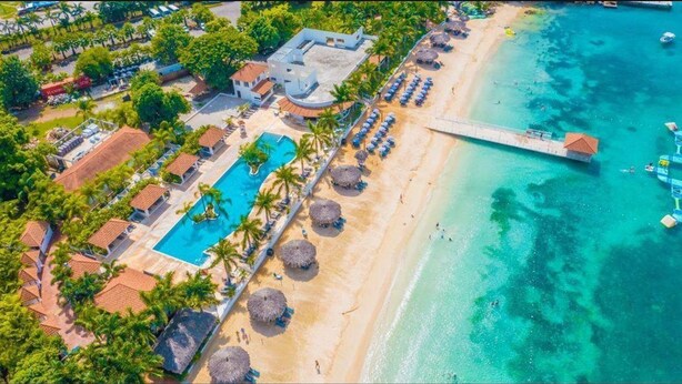 Vista aérea de un resort con piscina, playa y muelle.