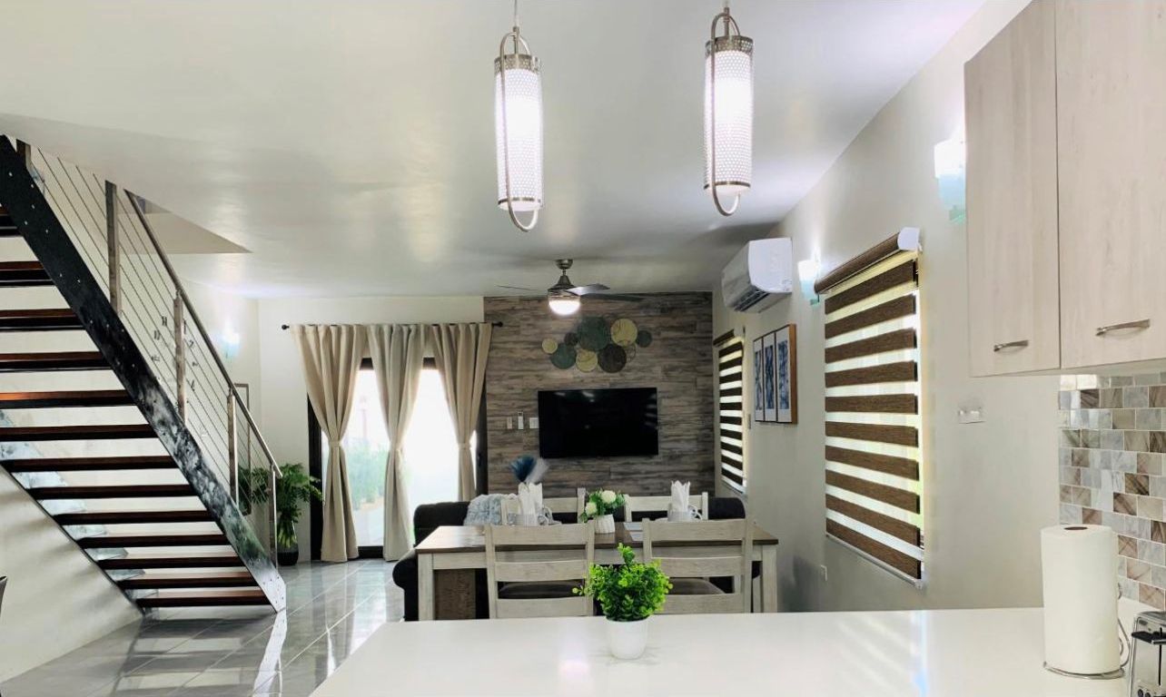 A modern kitchen with a central island, a dining area, and a staircase leading to another level.