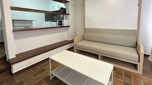A compact living space with a kitchenette, a sofa, and a small table. - Agi Porthos 111 Apartamento for rent in Roses Girona. (Roses)
