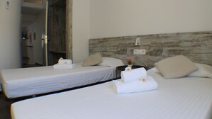 Habitación de hotel con dos camas individuales, cada una con cubrecama blanco, almohada y toalla con un estampado floral.