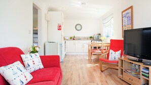A living room with a red sofa, a television, and a wooden entertainment unit.