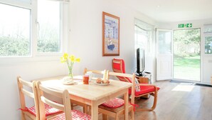 A room with a wooden table and chairs, a television, and a painting on the wall.