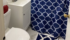 A bathroom with a white sink, a mirror, a toilet, and a blue patterned shower curtain.