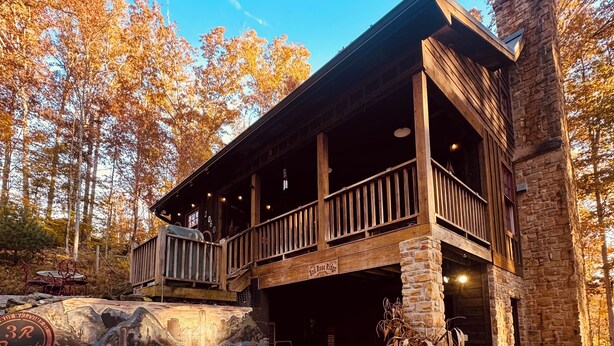 A rustic lodge with a wooden deck and stone walls, surrounded by autumn foliage. - Brown County At It's Best Beautiful Cozy meticulous clean LG Game Room arcade! (Nashville)